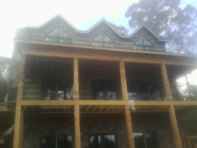 Dormers and porch framing on a large log home under construction — Roof Coating work by our crew in Stafford